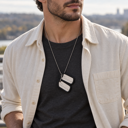 Man wearing a personalized silver dog tag necklace with black silencers over a charcoal T-shirt