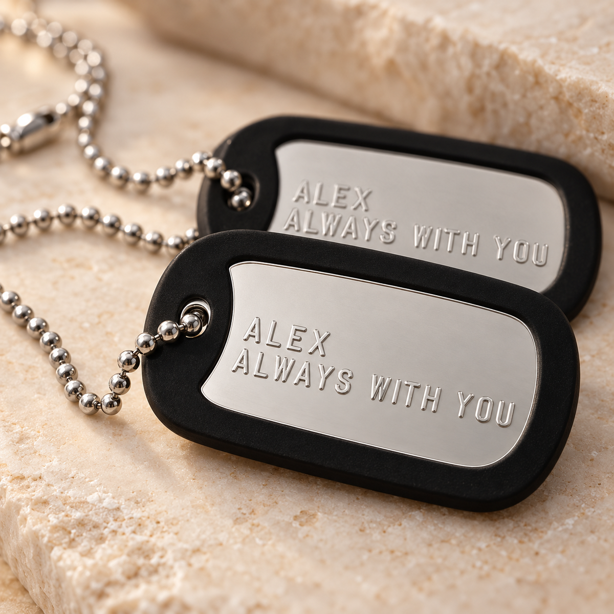 Close-up of raised lettering on a personalized silver dog tag with a removable black rubber silencer