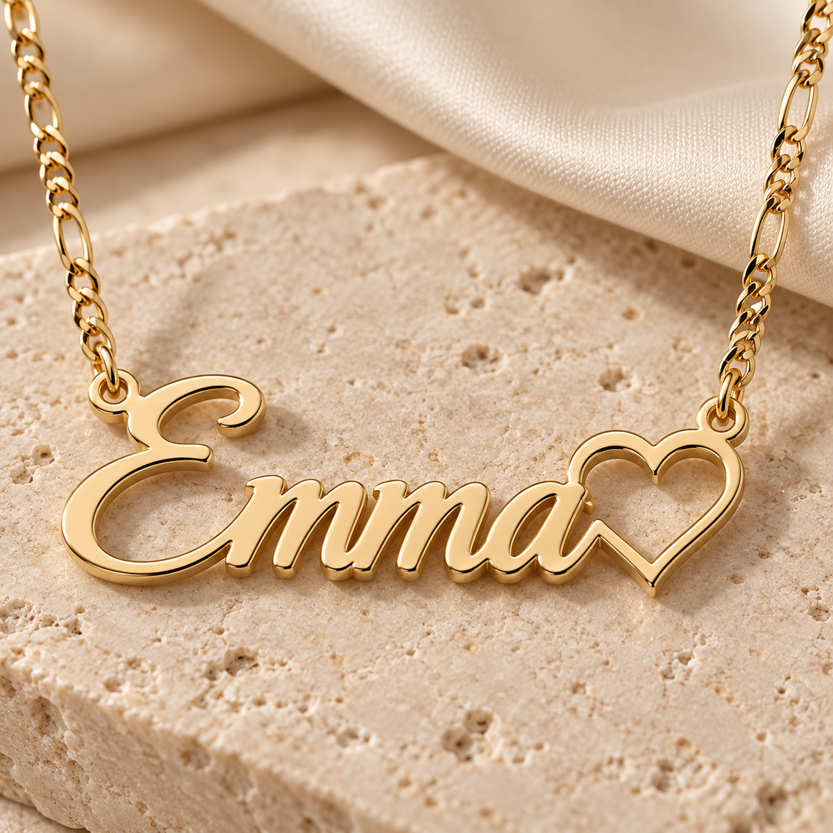 Close-up of a polished gold script name pendant with open heart detail